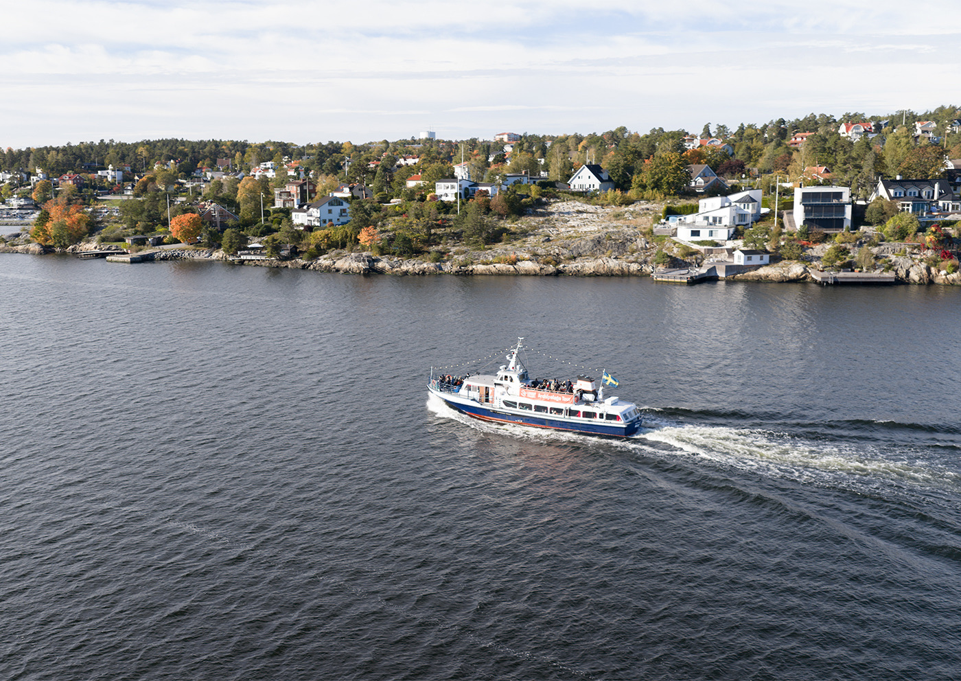 Sightseeingbåt på väg genom Stockholms skärgård förbi klippor och sommarhus